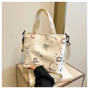 Détail du sac cabas en toile blanche avec imprimé graffiti et large bandoulière réglable