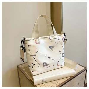 Détail du sac cabas avec imprimé artistique tacheté et poignées en tissu blanc