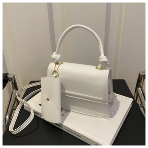 Close-up of white minimalist handbag with gold hardware and mini pouch accessory