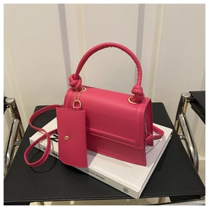 Detail of pink shoulder bag with knot handle and matching mini coin purse on book