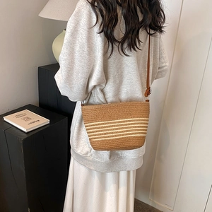 Straw crossbody bucket bag with white stripes and slim leather strap for summer beach vacation