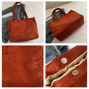 Detail of orange corduroy tote with floral embroidery and silver magnetic closure