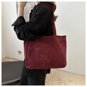 Detail of burgundy corduroy tote bag with traditional Chinese floral embroidery texture