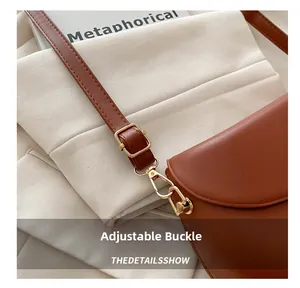 Detail of brown matte leather bag featuring golden adjustable buckles and fine stitching