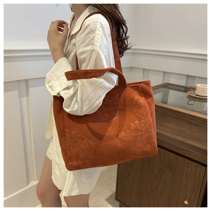 Detail of orange-brown corduroy tote bag featuring traditional floral jacquard patterns
