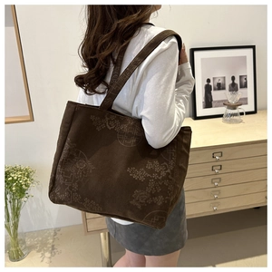 Detailed view of the brown corduroy tote bag with vintage floral patterns and wide strap