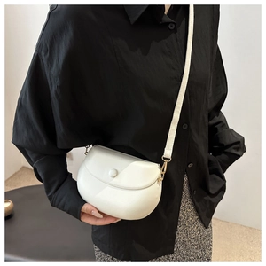 Detailed view of a white semi-circle saddle bag with gold metal buckles and smooth texture