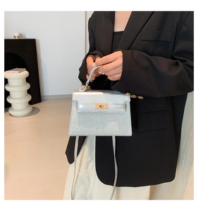 Detalle de la textura brillante de lentejuelas y cierre dorado en un mini bolso Kelly chic