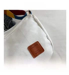 Close-up of canvas bag with brown leather patch and colorful striped shoulder strap