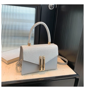 Close-up of silver glitter flap and gold metal clasp on a stylish handbag
