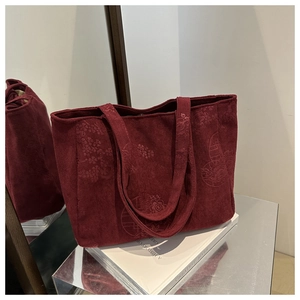 Detail of dark red corduroy tote bag showing floral embossing and vintage texture