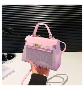 Detalle de bolso rosa en cuero y tejido con cierre de giro dorado y asa de mano