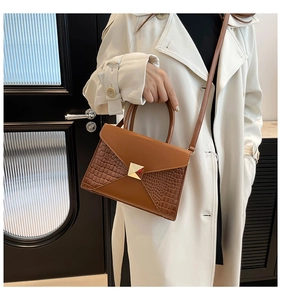 Close-up of brown patchwork handbag with crocodile texture and gold square buckle detail