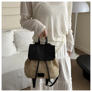 Detail of hand-woven straw backpack with black faux leather straps and trim for travel