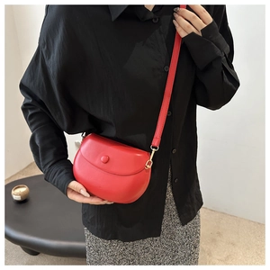 Sacoche selle rouge en cuir mat avec rabat porté par un mannequin en chemise