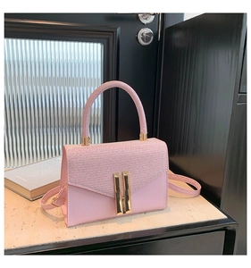 Detail of pink leather handbag with glitter texture and gold metal buckles on marble