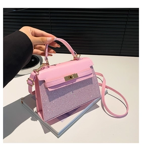 Detalle del bolso cuadrado rosa con panel brillante y cierre giratorio dorado