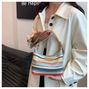 Detail of colorful woven shoulder bag with rainbow stripes and leather strap on model