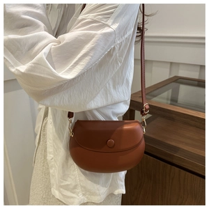 Détail d'un sac besace marron avec boucle en métal doré et rabat arrondi chic