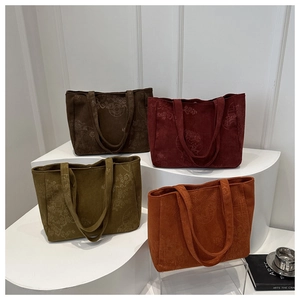 Detail view of corduroy tote bags with floral patterns in coffee, wine, green and orange