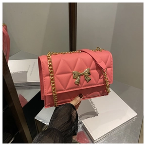 Detailed view of pink quilted handbag featuring a golden bow metal buckle and chain strap