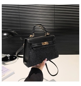 Detalle de mini bolso negro con lentejuelas, cierre de giro dorado y asa de cuero