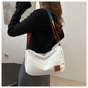 Detail of white canvas tote with vintage leather logo and stylish tricolor wide strap
