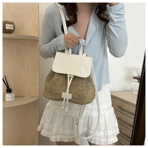 Straw and white leather backpack worn by model in a minimalist modern room setting