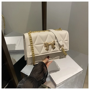 Detail of cream PU leather crossbody bag with geometric quilting and gold bow metal buckle