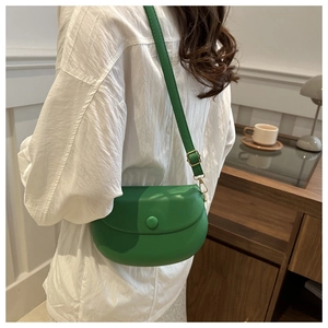 Détail du sac de selle en cuir vert avec boucles dorées et bandoulière réglable