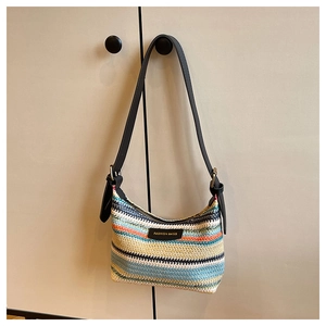 Detailed close-up of rainbow striped knit fabric with black leather shoulder strap