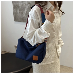 Close-up of retro navy canvas tote bag with multi-color strap and leather patch