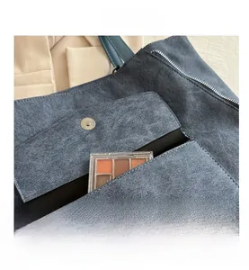 Détail du sac cabas en daim bleu montrant la poche extérieure à fermoir magnétique