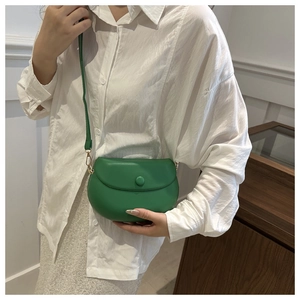 Green leather saddle bag with round metal buckle shown on a model for casual commuting