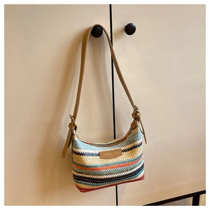 Detailed close-up of a colorful striped woven straw shoulder bag with leather accents