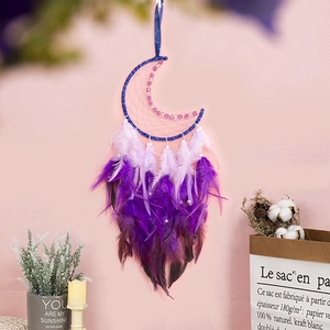 Capteur de rêves lune bleue avec plumes violettes et perles sur un mur rose doux