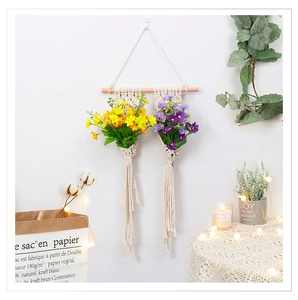 Dettaglio di fioriera sospesa boho in corda di cotone con doppia cesta, asta in legno e nappe