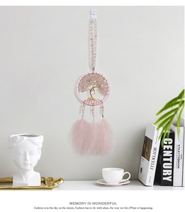 Pink crystal tree of life dreamcatcher with soft feathers hanging in a stylish home interior