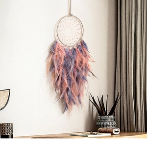 Detail of bohemian dream catcher with pink and purple feathers on a bedroom wall