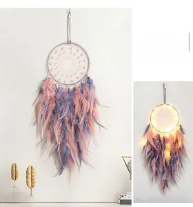 Detail of dream catcher with pink feathers, pearls and warm LED lights for room decor