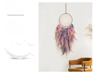 Detailed view of a handmade dreamcatcher with pink and purple feathers on a white wall