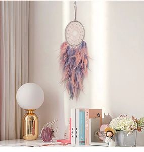 Close-up of handmade dreamcatcher featuring soft pink and purple feathers with pearls