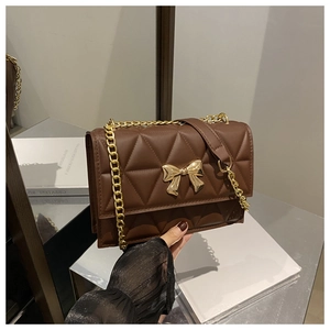 Close-up of dark brown quilted crossbody bag featuring a golden bow metal clasp and chain