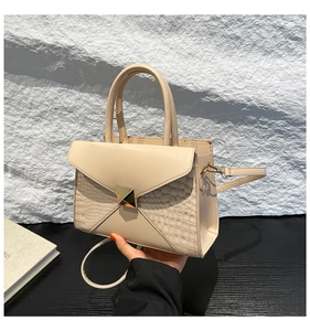 Détail du sac à main beige carré avec texture crocodile et boucle en métal doré