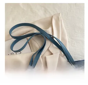 Détail du sac cabas en daim bleu avec des anses confortables et une fermeture éclair