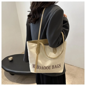 Modern oversized canvas tote bag with contrast leather handles and minimalist logo print