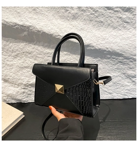 Détail du sac bandoulière noir avec texture crocodile et boucle en métal doré
