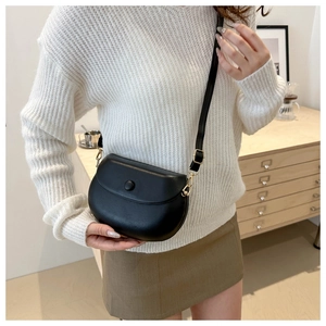 Détail d'un sac besace noir minimaliste avec texture lisse et boucle en métal doré