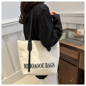 Detail of canvas tote bag with contrast leather straps and printed letter design