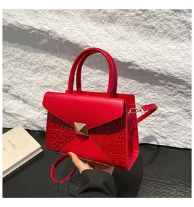 Gros plan d'un sac à main rouge avec motif crocodile et boucle en métal doré